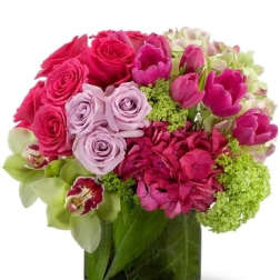 Pink and lavender roses with tulips in a glass vase