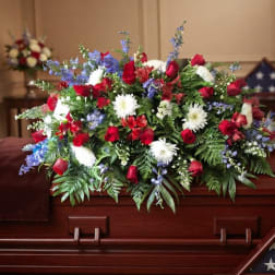 Red, white, and blue floral spray arranged on a wooden casket