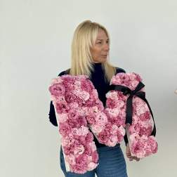 Woman holding two large pink floral letter arrangements