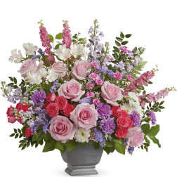Mixed pink and purple flower arrangement in a gray pedestal vase