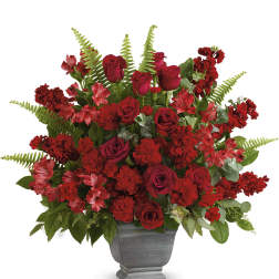 Red roses and carnations arranged in a gray urn vase