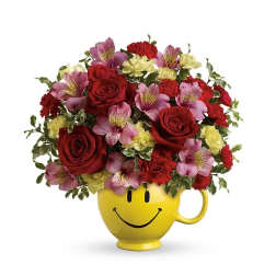 Bouquet of red roses, pink alstroemeria, and yellow carnations in a yellow smiley-face mug