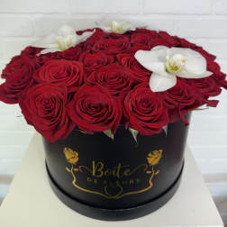 Red roses and white orchids arranged in a black round box