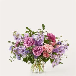 Pink and lavender roses arranged in a clear glass vase