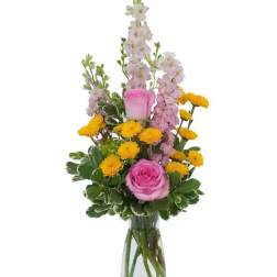 Pink roses and yellow pompon flowers in a clear glass vase