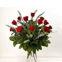 Red roses arranged in a clear glass vase with eucalyptus