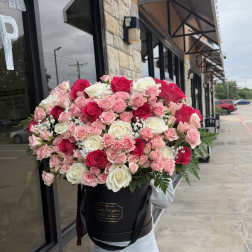Large bouquet of pink and white roses in a black hatbox