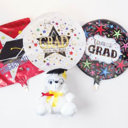 Three graduation balloons with a small teddy bear