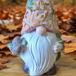 Decorative gnome figurine holding pinecones on an autumn background