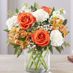 Orange roses and white carnations in a clear glass vase