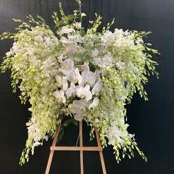 Large white orchid arrangement on a wooden easel