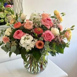 Mixed bouquet of pink and peach roses in a clear glass vase