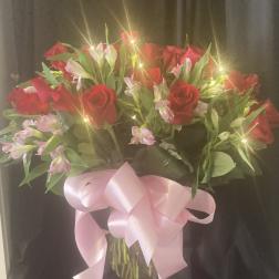 Bouquet of red roses and pink alstroemeria in a glass vase with a pink ribbon