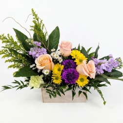 Mixed bouquet in a wooden box with peach roses, purple blooms, and yellow daisies