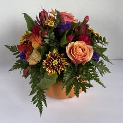Mixed bouquet of roses and chrysanthemums in an orange pumpkin container