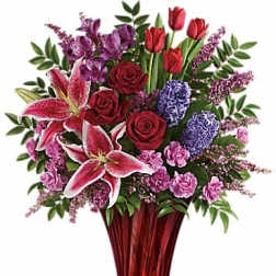 Bouquet of red roses, pink lilies, and purple flowers in a red vase