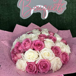 Bouquet of pink and white roses wrapped in pink paper