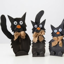 Three black cat figurines with burlap bows on a white background