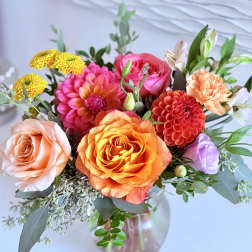 Mixed bouquet of roses, dahlias, and chrysanthemums in a glass vase
