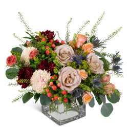 Mixed bouquet of roses, chrysanthemums, and berries in a clear square vase