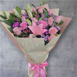 Pink rose and lily bouquet wrapped in patterned paper with a pink ribbon