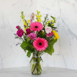 Pink gerbera daisies and mixed flowers in a glass vase