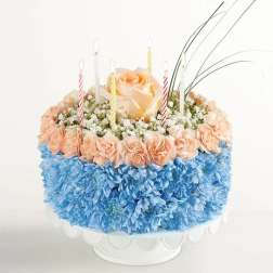 Round floral cake with peach roses, blue flowers, and striped candles