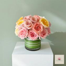 Pink and yellow roses arranged in a striped glass vase