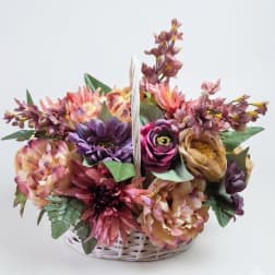 Basket arrangement of multicolored flowers in pink, purple, and peach tones