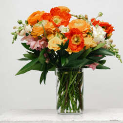 Orange and pink mixed bouquet in a clear glass vase