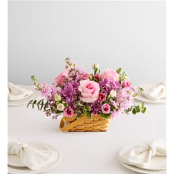 Pink and purple flower arrangement in a woven basket on a table