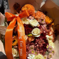 Bouquet of orange, burgundy, and cream flowers with an orange ribbon