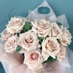 Bouquet of pale blush roses wrapped in pink paper