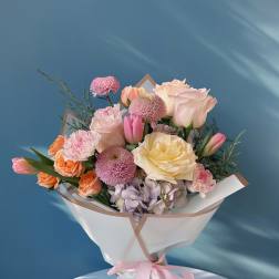 Pastel bouquet of roses, tulips, carnations, and chrysanthemums wrapped with a pink ribbon