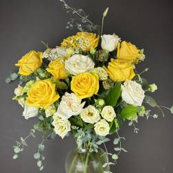 Yellow and white roses arranged in a clear glass vase