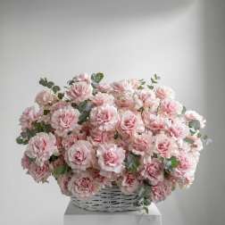 Pink roses in a white wicker basket with eucalyptus accents