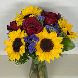 Bouquet of red roses and yellow sunflowers in a glass vase