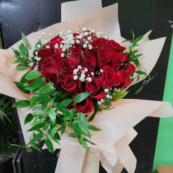 Bouquet of red roses with white baby's breath and greenery in cream wrap