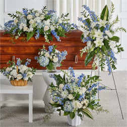 White and blue funeral floral arrangements around a casket