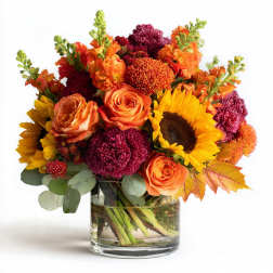 Bouquet of orange roses, sunflowers, and burgundy mums in a glass vase