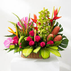 Tropical flower arrangement in a wicker basket with pink roses and orchids