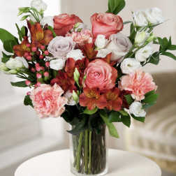 Mixed bouquet of pink, white, and orange flowers in a clear glass vase
