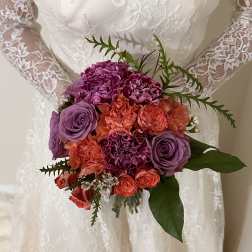 Bride holding a bouquet of purple and coral flowers