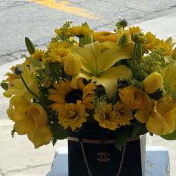 Yellow floral arrangement in a black handbag-style container