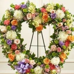 Large floral wreath on a black easel with a purple ribbon