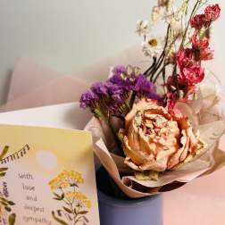 Bouquet of dried flowers in a blue vase beside a sympathy card