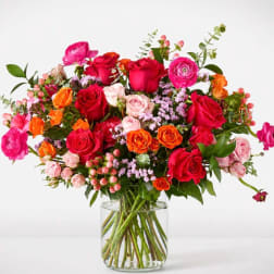 Mixed bouquet of roses and ranunculus in a clear glass vase
