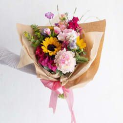 Mixed bouquet with sunflowers, pink blooms, and kraft paper wrapping