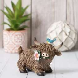 Decorative cow figurine with a flower and bird on its head