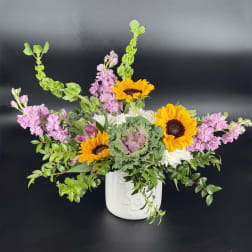 Sunflower and pink flower arrangement in a white ceramic vase